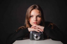 Portrait professionnel d'une jeune femme réalisé en studio chez Kodak Express Tourcoing, posant avec un appareil photo vintage