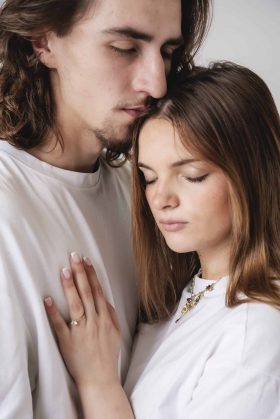 Plan serré d'un couple habillé de blanc, les yeux fermés et tête contre tête, exprimant un moment de douceur et de sérénité