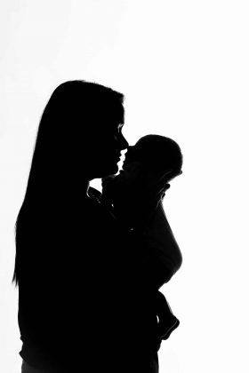 Silhouette en contre-jour artistique d'une maman tenant son nouveau-né, séance photo studio créative sur la métropole lilloise