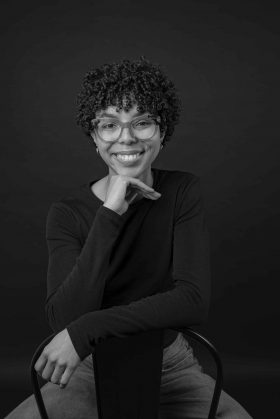 Version noir et blanc d'un portrait professionnel féminin, la main sous le menton, dégageant intelligence et sérieux pour un CV