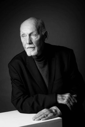 Portrait distingué en noir et blanc d'un homme senior en costume sombre, regardant au loin, inspirant sagesse et autorité