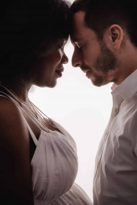 Plan rapproché d'un couple attendant un enfant, front contre front dans une lumière douce, photo de maternité artistique réalisée en studio sur la métropole lilloise