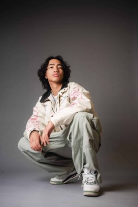 Portrait artistique d’un homme accroupi en studio, tenue contemporaine