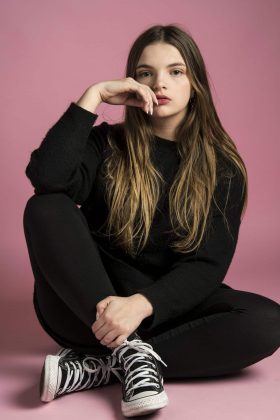Portrait artistique d’une femme sur fond rose, regard caméra