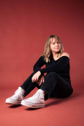 Portrait artistique d’une femme assise en studio sur fond rouge