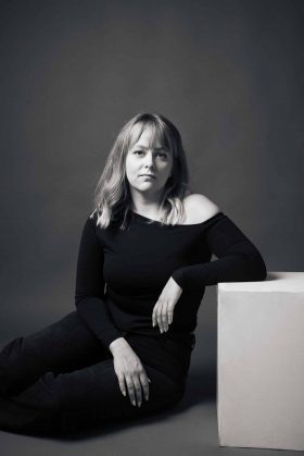 Portrait noir et blanc d’une femme assise en studio, pose naturelle